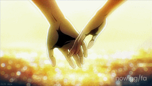 Two people gently holding hands in golden light